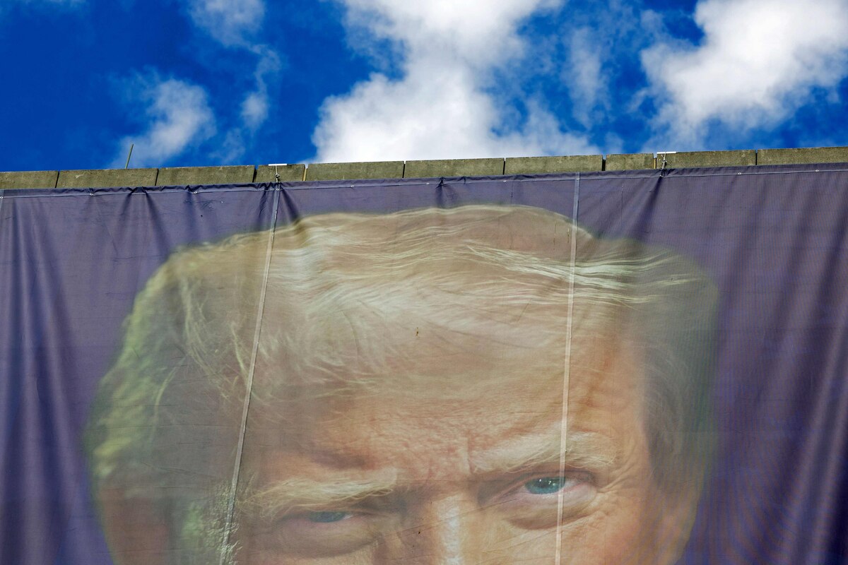 A large photo of US President Donald Trump hangs on the facade of the Department of Labor headquarters building during the "No Kings" national day of protest in Washington, DC on October 18, 2025. From New York to San Francisco, millions of Americans are expected to hit the streets to voice their anger over President Donald Trump's policies at nationwide "No Kings" protests. (Photo by Amid FARAHI / AFP)