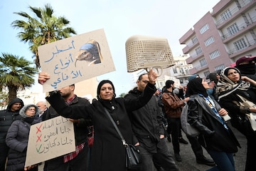 Tunisians hold up placards as they demonstrate in a protest dubbed 'March Against Injustice' led by the opposition and the civil society against the Tunisian president's regime, in Tunis on November 22, 2025. Since the Tunisian president staged a sweeping power grab in 2021 -- in what critics have called a coup -- rights groups have denounced a regression in freedoms in the country. (Photo by FETHI BELAID / AFP)