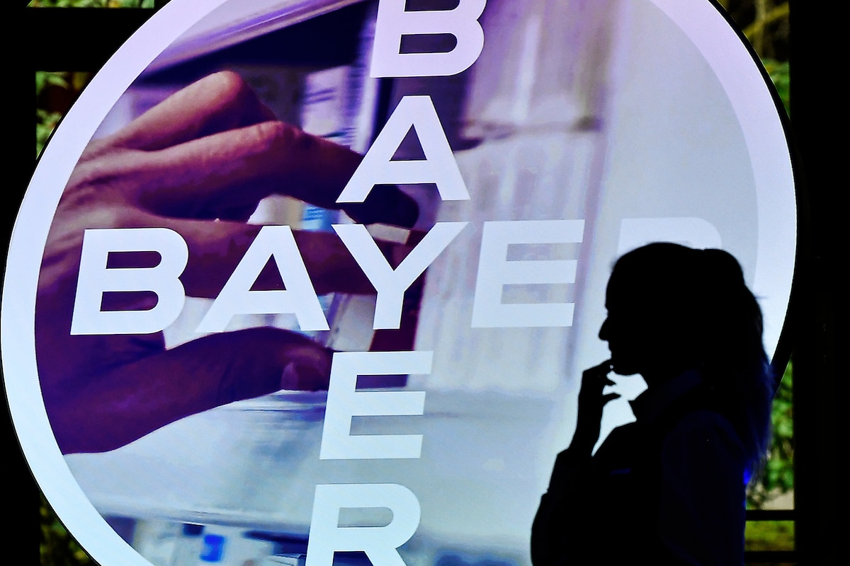 FILE - A woman walks in front of a logo of Bayer AG at the Financial News Conference in Leverkusen, Germany, Feb. 27, 2020. (AP Photo/Martin Meissner, File)