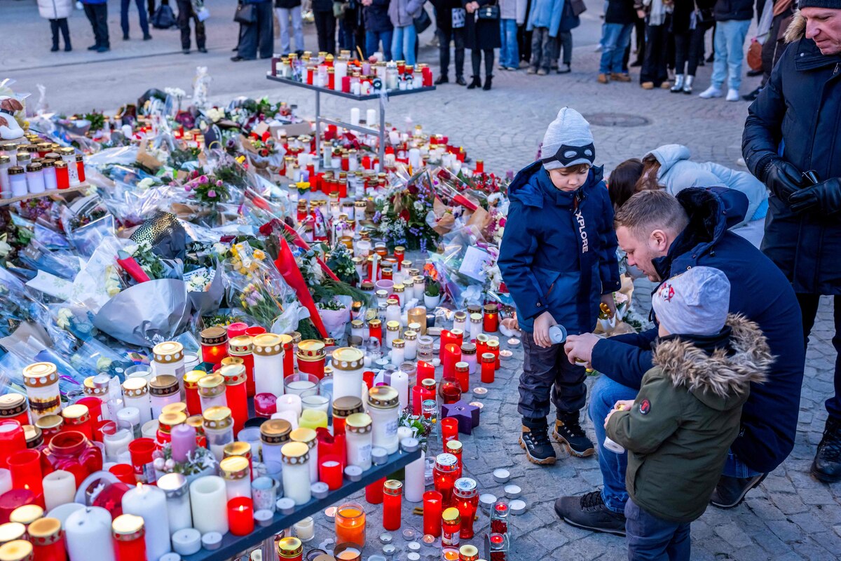 People gather around a makeshift memorial to pay their respects by laying flowers, candles and messages near the Constellation bar, on January 4, 2026, in Crans-Montana in honour of the victims of the fire that ripped through the venue in the luxury Alpine ski resort on New Year's Eve. Authorities investigating the New Year's blaze in the Swiss resort of Crans-Montana have identified 24 of the 40 people killed, including 11 minors and six foreign nationals, police said on January 4, 2026. Also 119 were injured during the fire, most of them seriously, according to the latest toll. (Photo by MAXIME SCHMID / AFP)